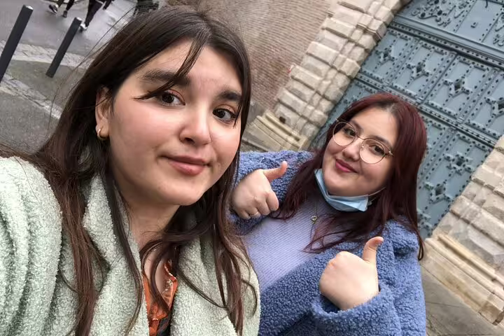 Two young women smiling for a selfie on a walking tour in Toulouse, one giving thumbs up