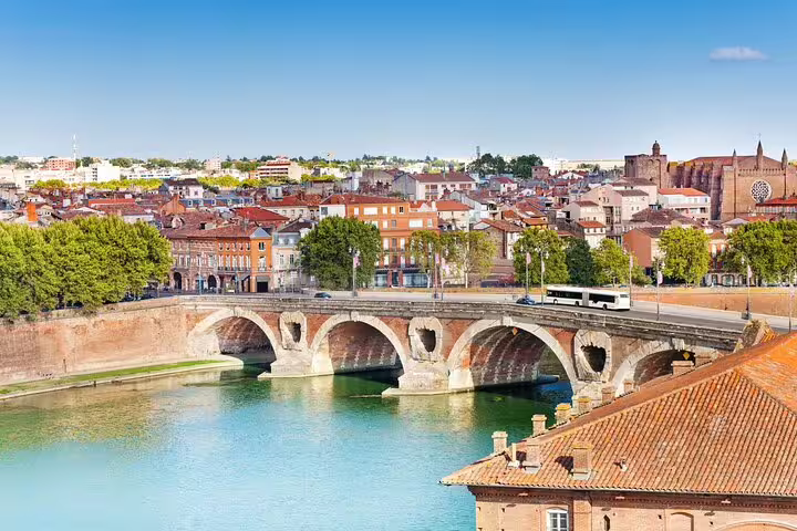 Pont Neuf stone bridge over the Garonne River with Toulouse pink brick cityscape in background