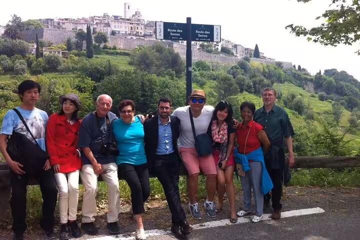 Tour group posing at Route des Serres sign with Saint-Paul-de-Vence hilltop village in background
