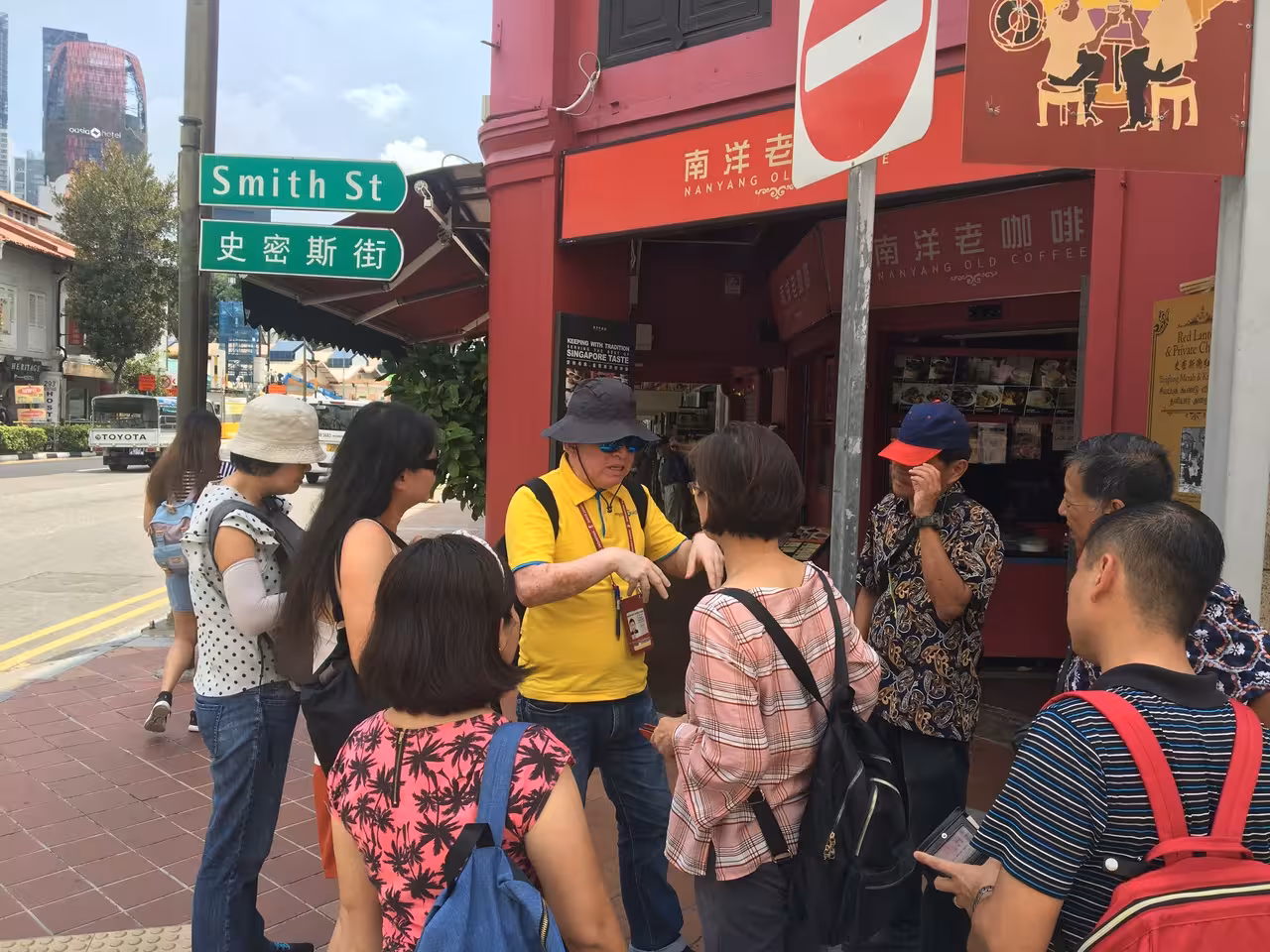 Tour guide explaining local history to a group on Smith Street, Chinatown, Singapore walking tour.