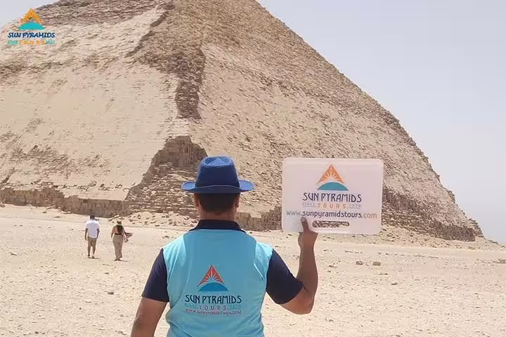 Tour guide at the Great Pyramid of Giza holding Cairo tour sign, included in 5-day Cairo vacation package