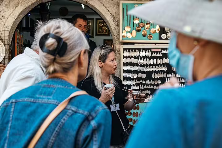 Tour guide presenting local crafts in Mostar Old Bazaar during scheduled Mostar and Kravice Waterfalls day trip