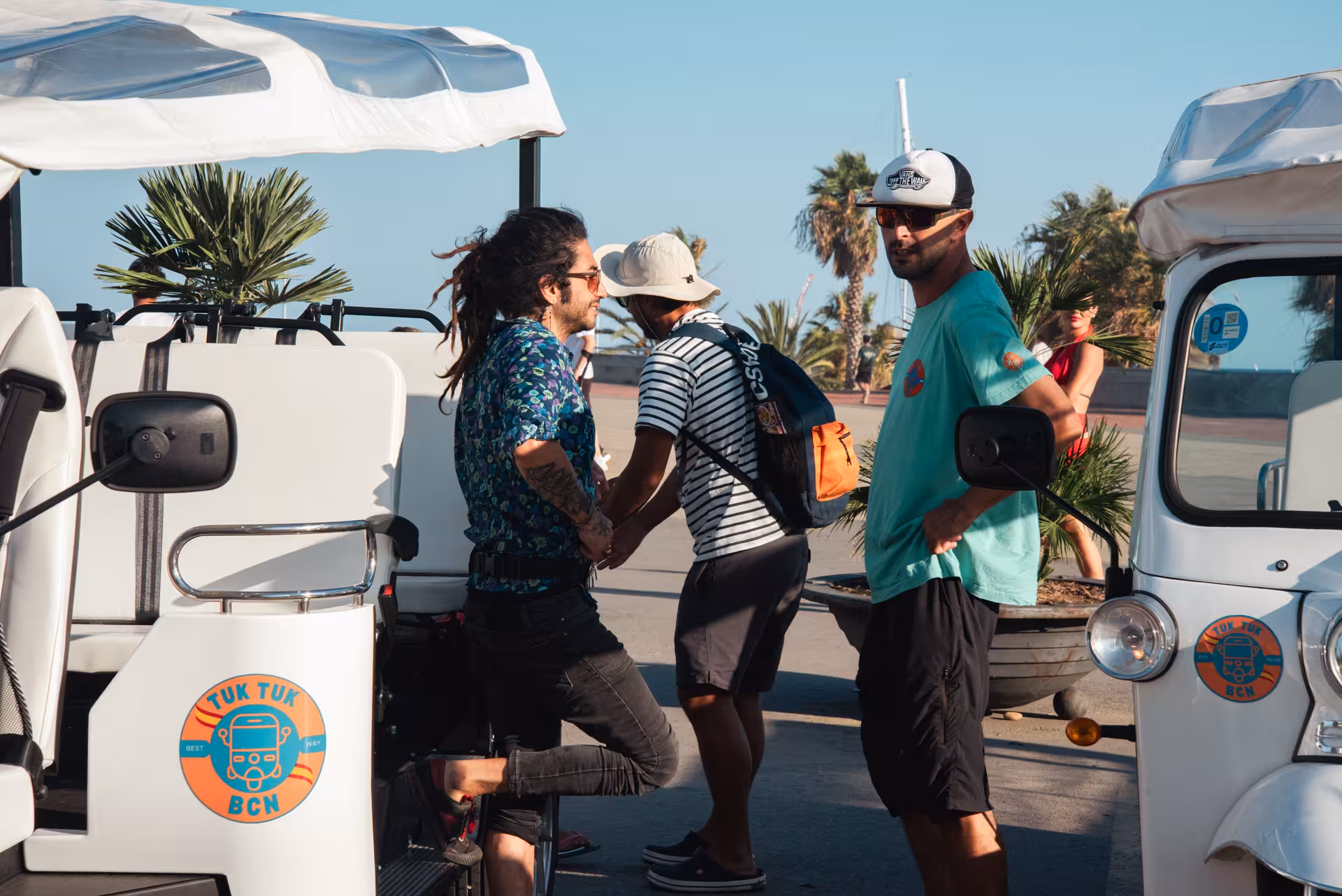 Tour guide welcoming guests beside tuk tuks before a full city highlights tour, with palm-lined promenade views