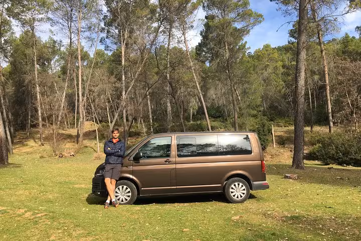 Tour guide standing by a van amidst a serene forest setting on a tropical hike near Malaga.