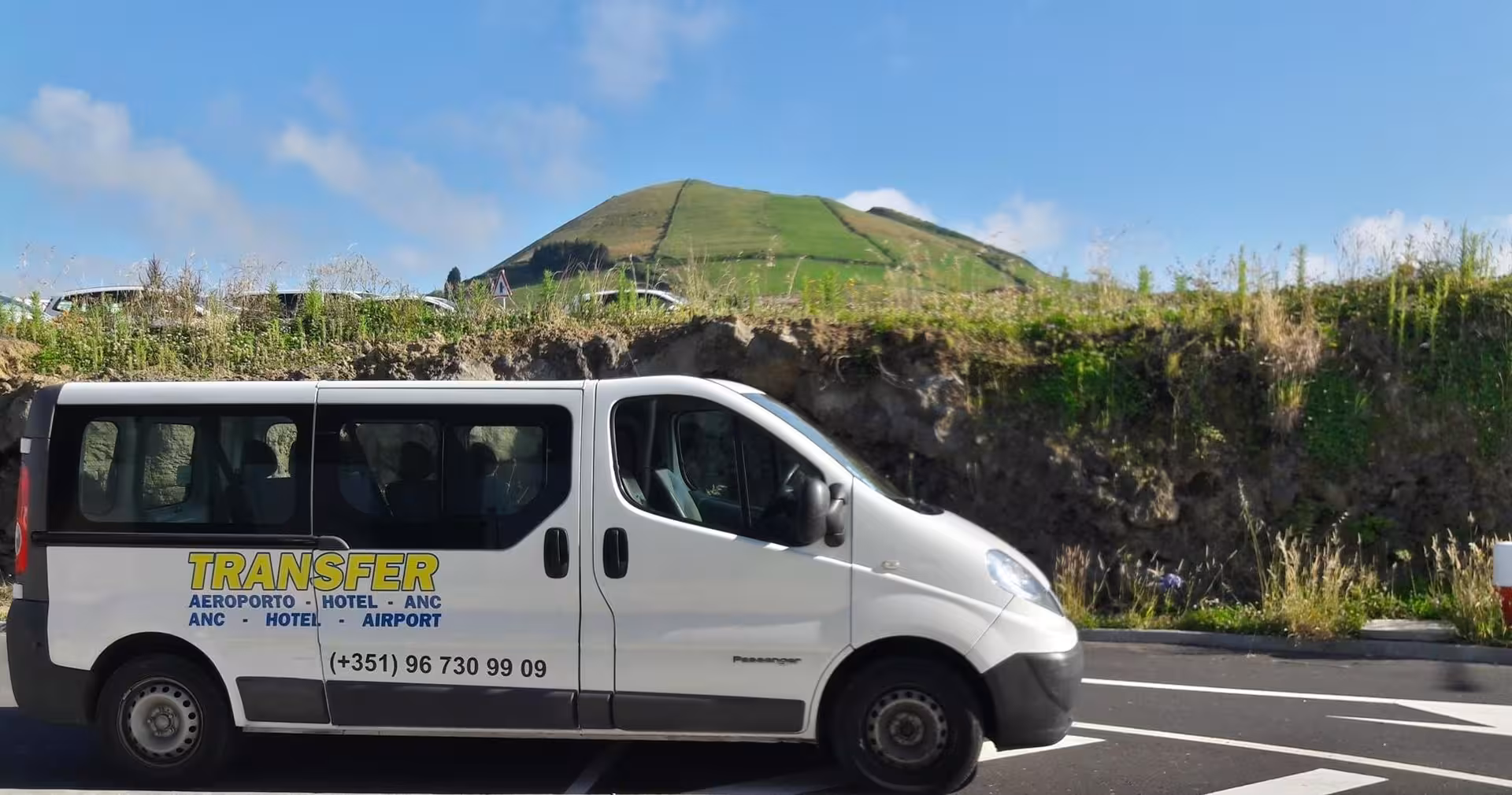 Tour van transfer parked on roadside in São Miguel, Azores, with lush green volcanic hill en route to Sete Cidades