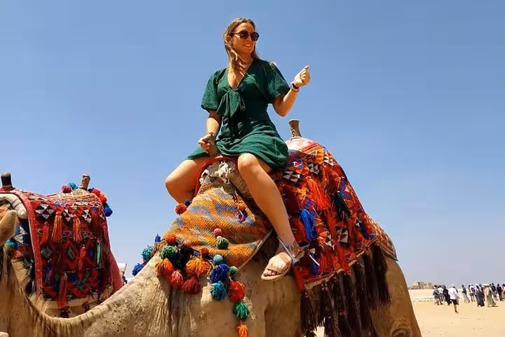 Tourist riding a decorated camel in Giza Desert on Cairo day trip to Pyramids, Sphinx and Grand Egyptian Museum