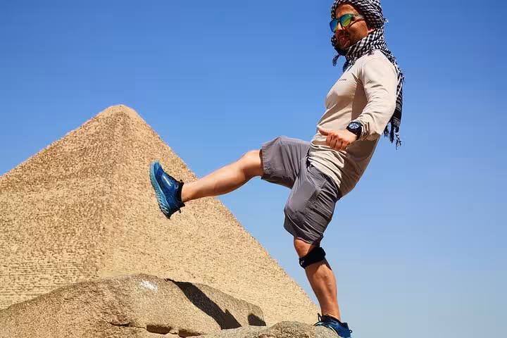 Tourist posing by a Giza pyramid under blue sky on Grand Egyptian Museum and Giza Pyramids tour with lunch