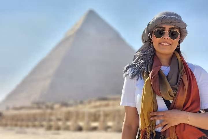 Tourist smiling by the Great Pyramid of Giza on a half-day Pyramids and Sphinx tour with lunch in Cairo