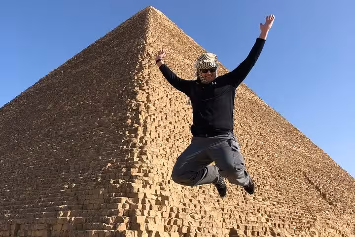 Tourist jumping in front of the Great Pyramid of Giza on an all-inclusive tour with pyramid entry and Sphinx visit