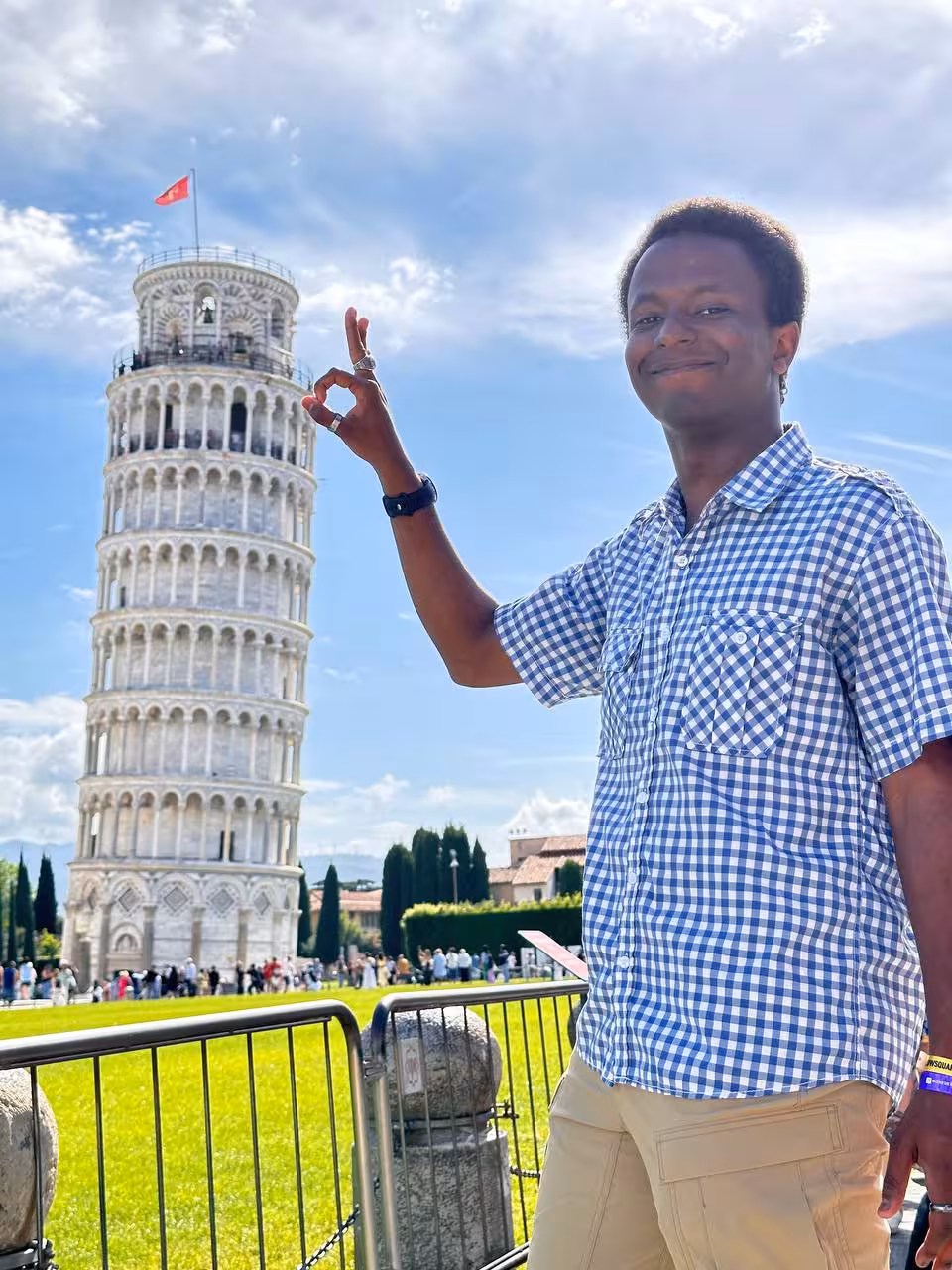 Tourist posing creatively with the Leaning Tower of Pisa on a sunny day, highlighting a popular tour attraction.