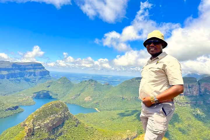 Smiling tourist at a stunning scenic overlook, showcasing panoramic views of verdant mountains and a winding river.
