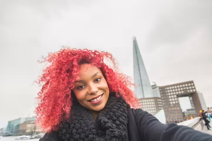 Smiling tourist with vibrant red hair takes a selfie in front of The Shard during a Private London Kickstart City Tour.