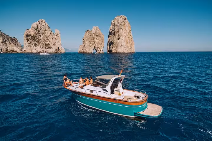 Tourists relaxing on a stylish boat near the stunning Faraglioni rocks of Capri.