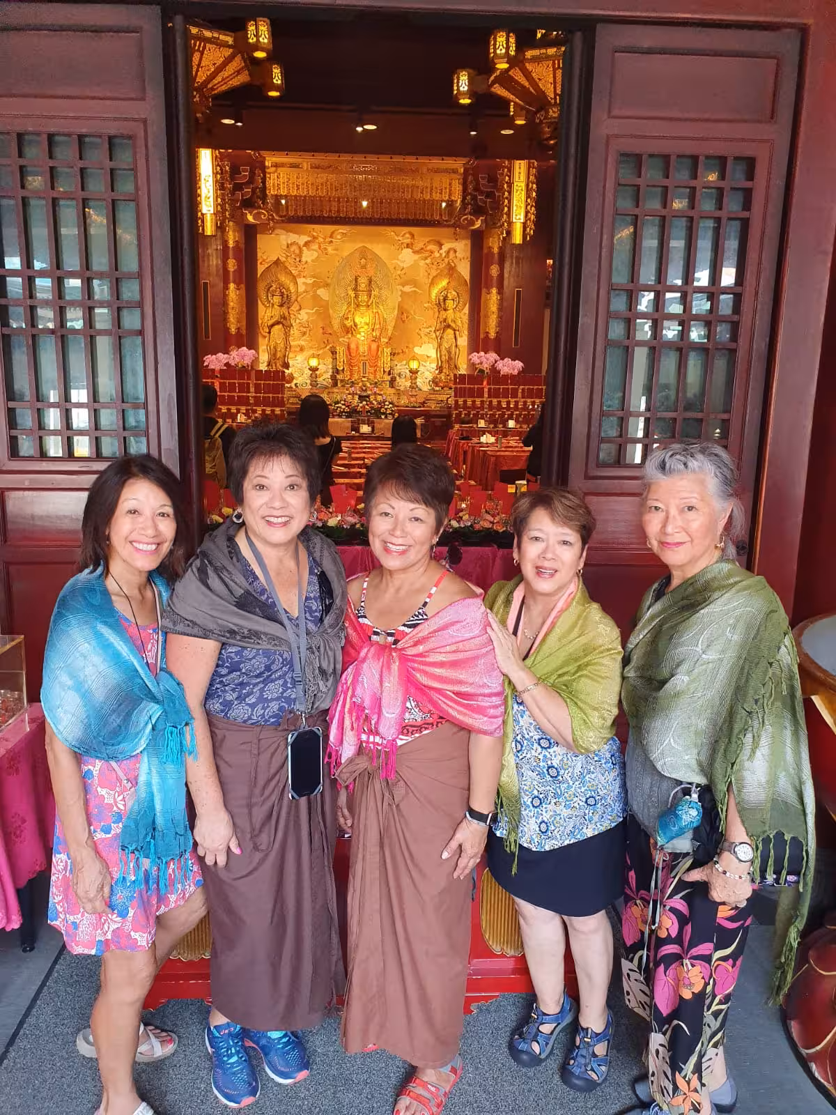 Group of tourists in colorful attire exploring the Buddha Tooth Relic Temple, Singapore tour guide service.