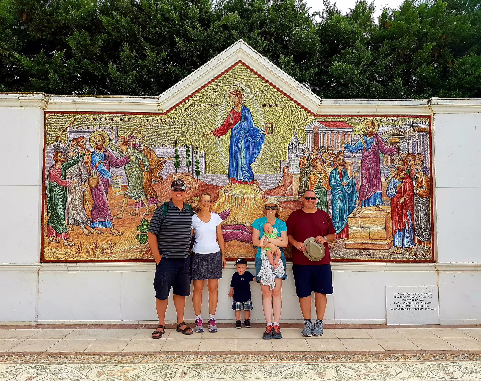 Tourists pose by a colorful Byzantine mosaic near Ancient Corinth on a private day trip from Athens