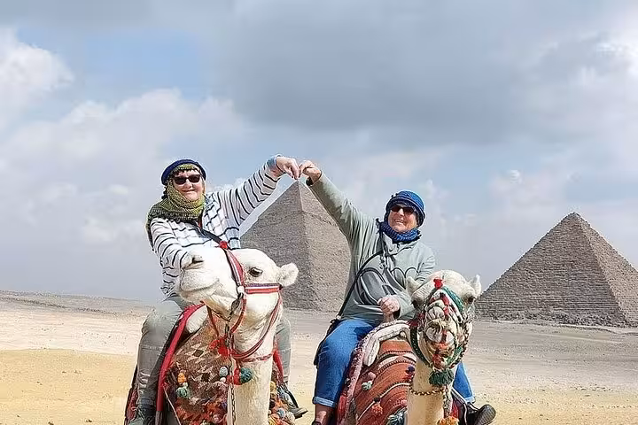 Tourists riding camels at Giza Pyramids on private Cairo day trip from Sharm El Sheikh by domestic flight