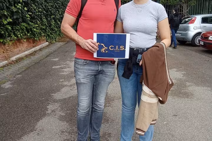 Two tourists holding a C.I.S. sign, ready for the Domus Aurea virtual reality tour in Rome.