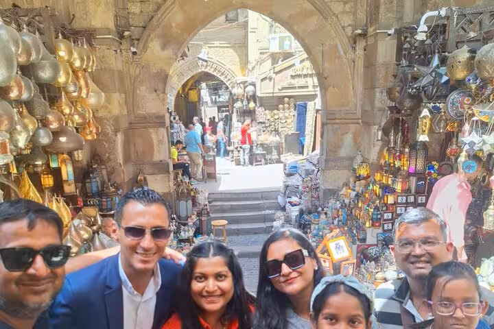A group of tourists explores a vibrant Egyptian bazaar, surrounded by colorful lanterns and traditional market stalls.