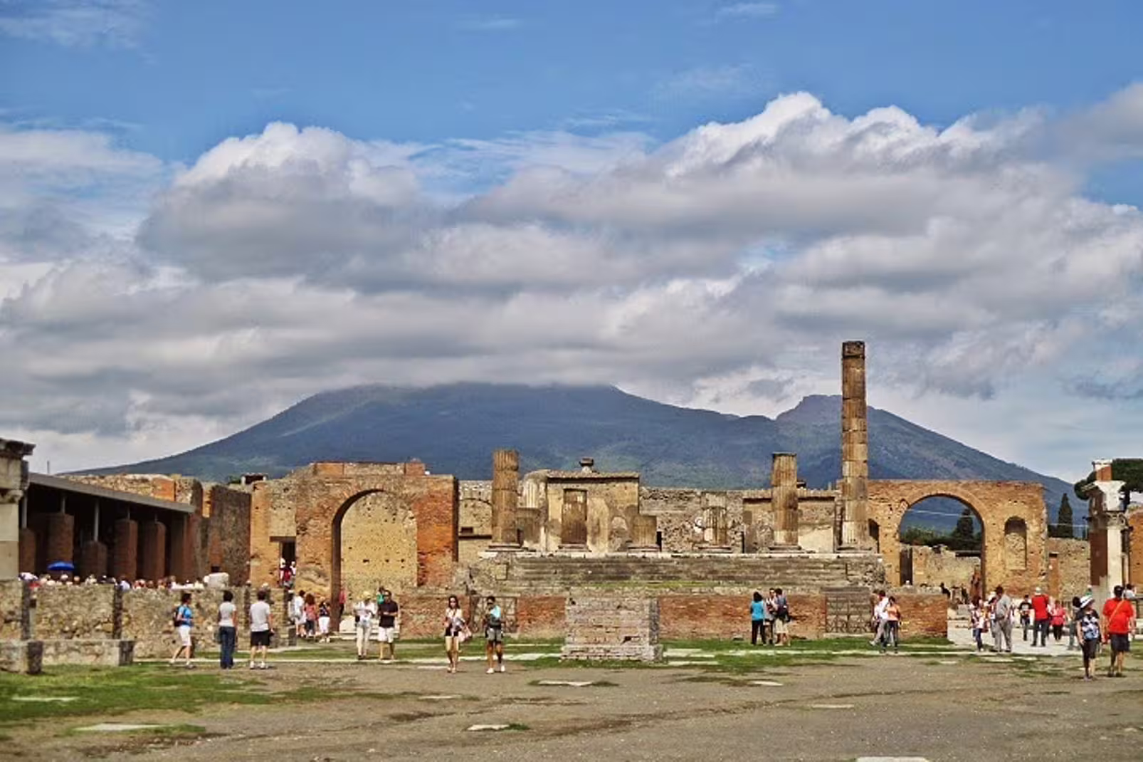 Tourists walking through the Forum ruins of Pompeii with Mount Vesuvius in the background on a shared Positano and Pompei excursion