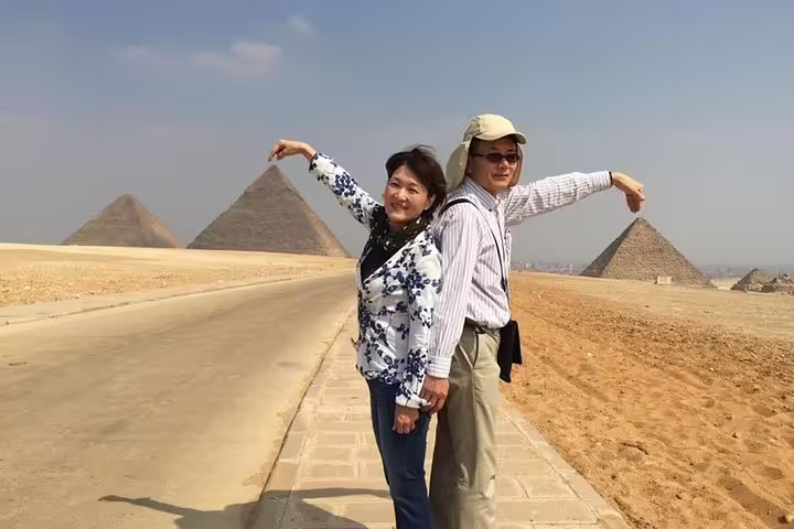 Tourists posing by Giza Pyramids on private Cairo Airport layover tour with fast pickup and guide