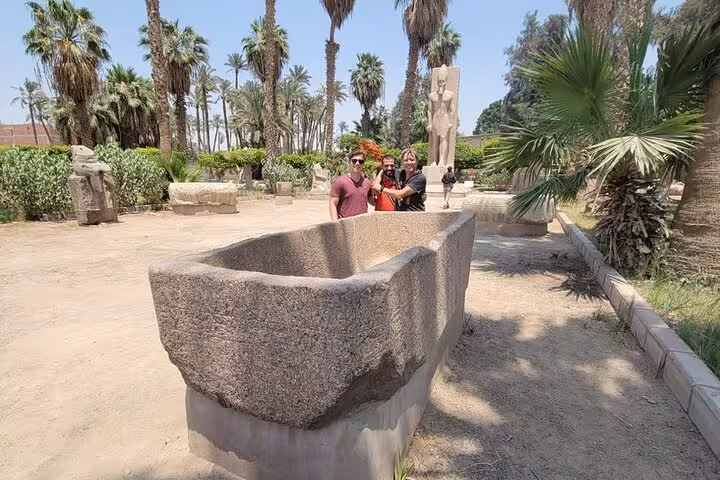 Tourists at Memphis open-air museum beside ancient granite sarcophagus on private Giza, Saqqara tour