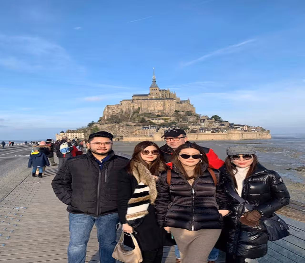 Group of tourists posing on the causeway in front of Mont Saint-Michel abbey, Normandy, France