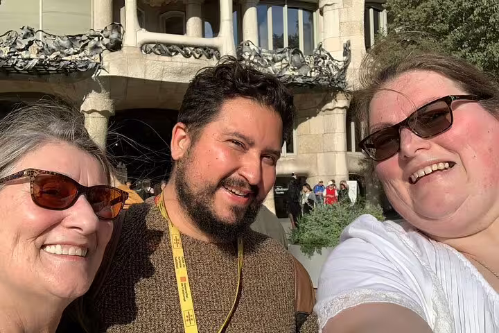 Smiling tourists enjoying a sunny day at Park Güell, Barcelona, with iconic architecture in the background.