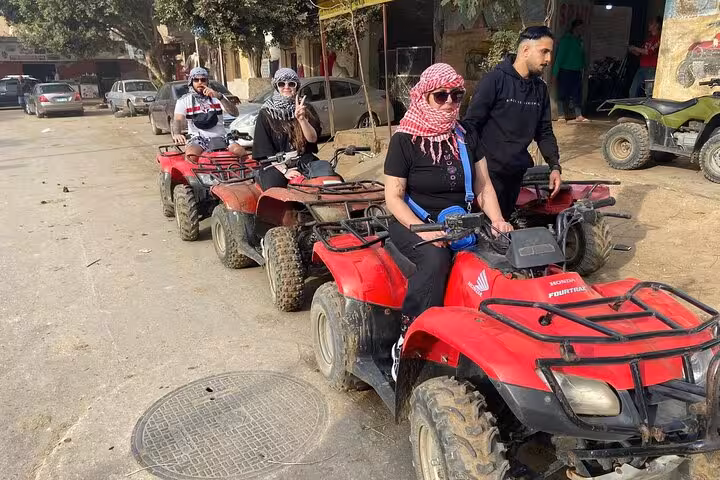 Tourists on red quad bikes in Cairo, part of desert safari with camel ride, lunch and shopping stop