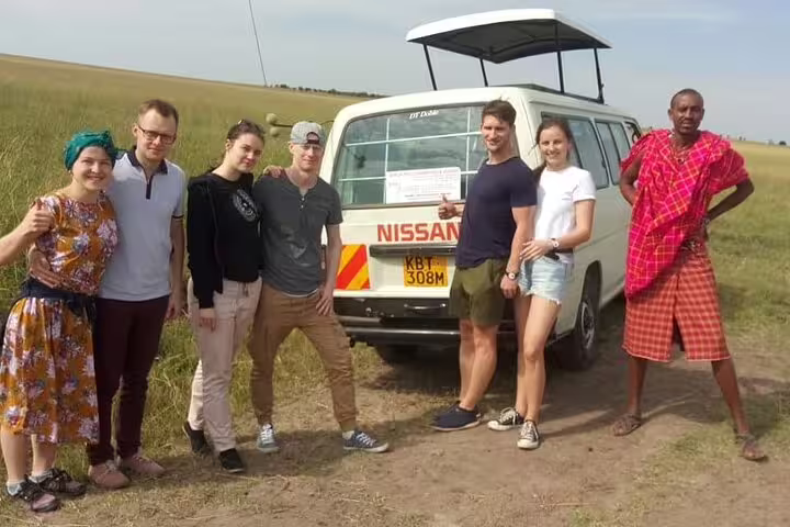 Group of tourists posing by a safari van in the open savannah during a 3-day Amboseli adventure from Nairobi.