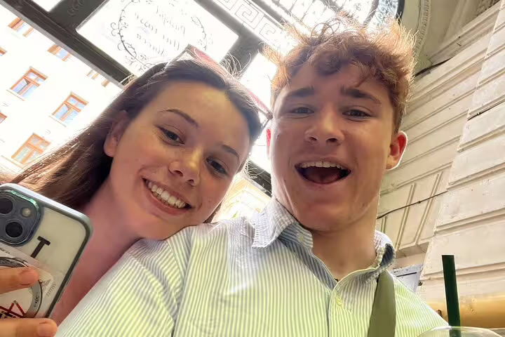 Two young tourists smiling and taking a selfie during a walking tour in Bucharest Old Town