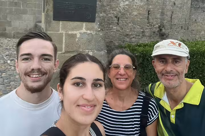 Group of four tourists smiling in front of Carcassonne medieval stone wall