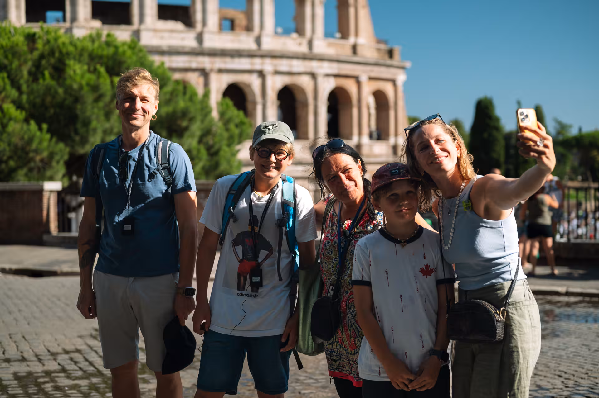 Group of tourists taking a selfie in front of the Colosseum, enjoying their Roman Forum and Palatine Hill tour.