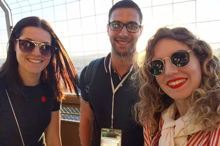Three smiling tourists wearing sunglasses taking a selfie at the top of the Eiffel Tower in Paris