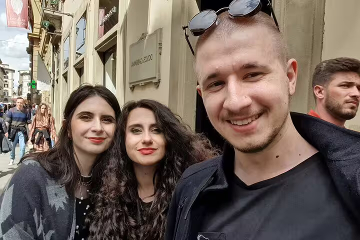 Three smiling tourists posing together on a Florence street during a self-guided walking tour