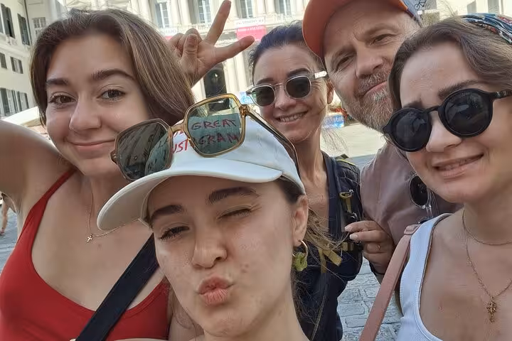 Group of five tourists taking a fun selfie in Genoa's historic medieval streets