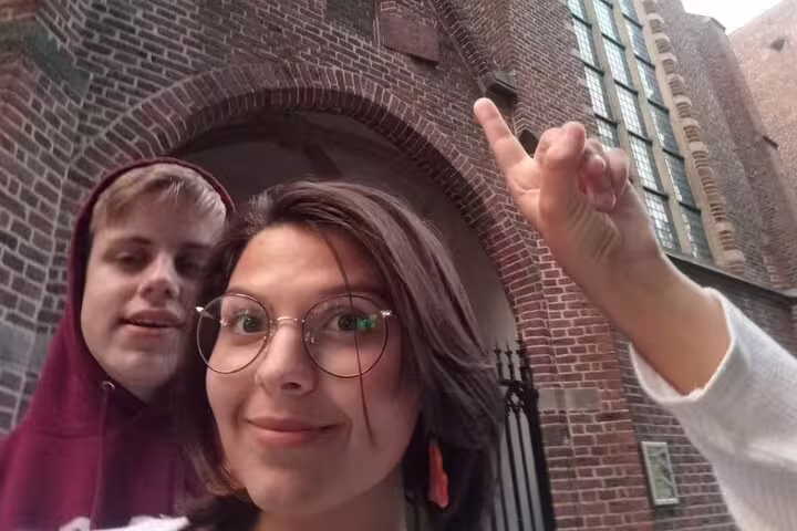 Two tourists taking a selfie in front of a historic brick archway in Utrecht