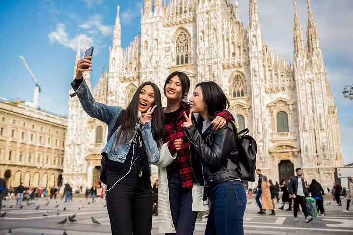 Tourists enjoying a selfie in front of Milan's iconic Duomo Cathedral during a private walking tour, capturing unforgettable moments.