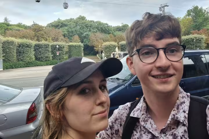 Two young tourists taking a selfie near Montjuic park with cable cars and hedges in background