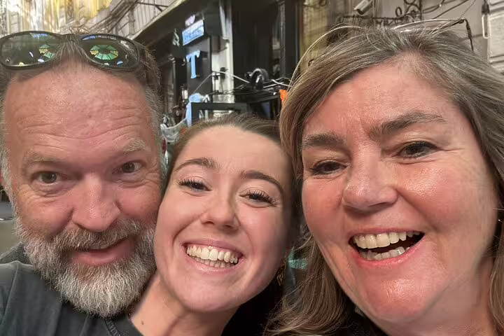 Three smiling tourists on a walking tour in Bucharest Old Town street