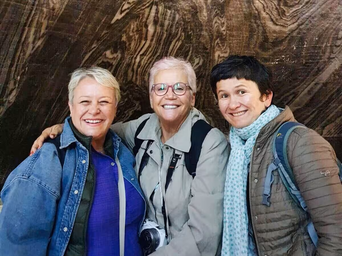 Three happy tourists smiling inside Turda Salt Mine during a guided day trip from Cluj Romania