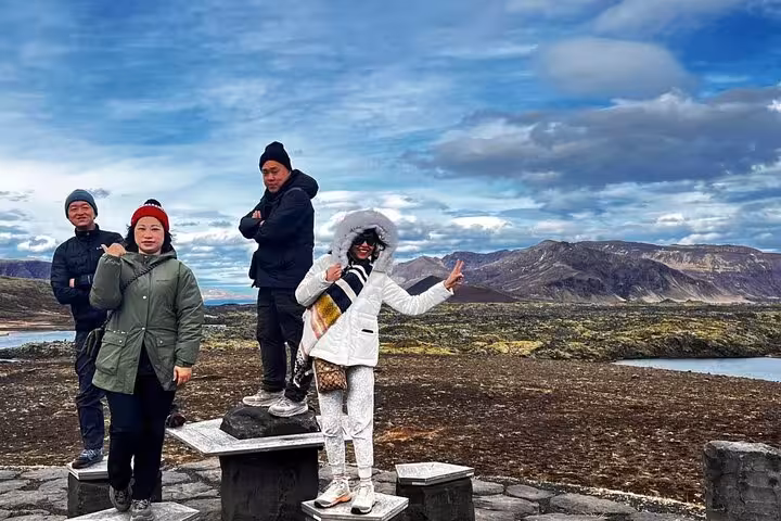 Group of tourists posing at scenic Snaefellsnes Peninsula viewpoint with volcanic landscape and mountains in background