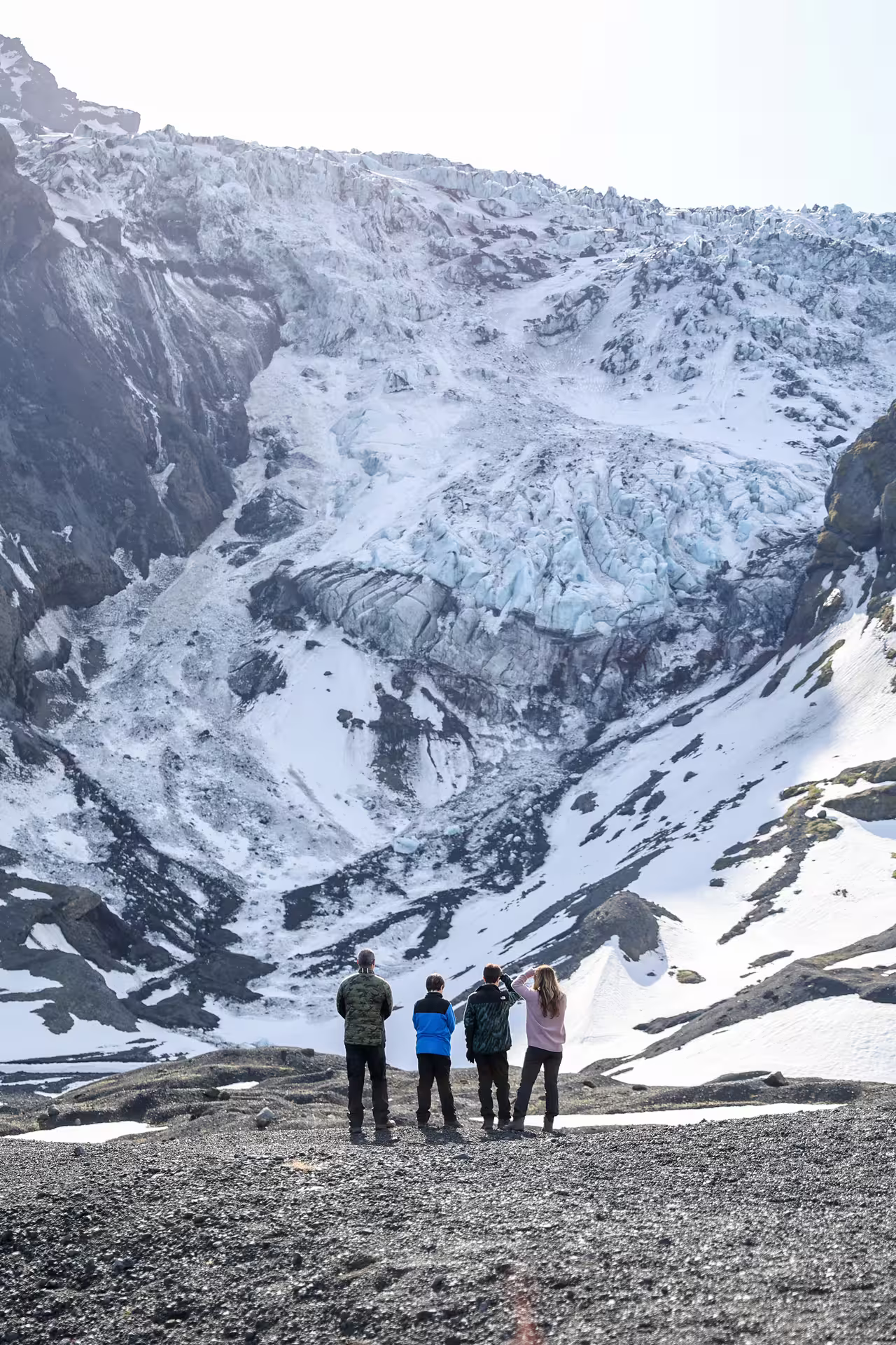 Four tourists marveling at a massive Icelandic glacier up close during a thrilling Thorsmork full-day 4x4 tour from Reykjavik.