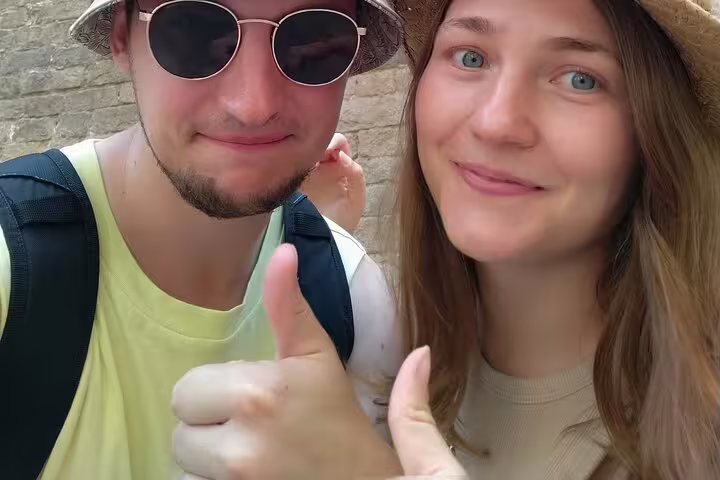 Two smiling tourists giving thumbs up during Barcelona Gothic Quarter walking tour
