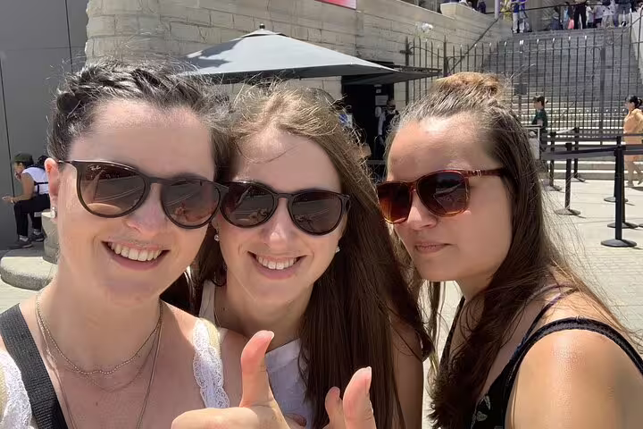 Three smiling women wearing sunglasses giving thumbs up on a sunny day in Barcelona city center