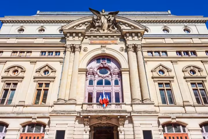 Ornate French neoclassical building facade with French flags and angel sculpture in Tours, France