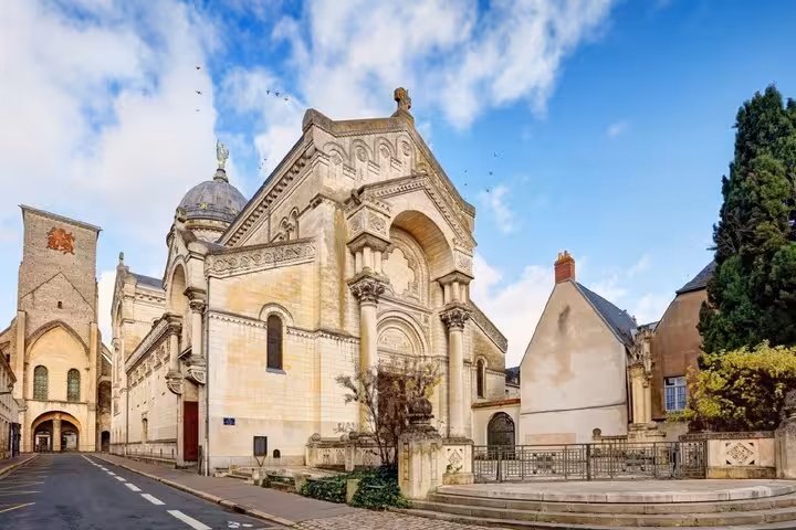 Historic ornate stone church facade on a cobblestone street in Tours, France, under a blue sky
