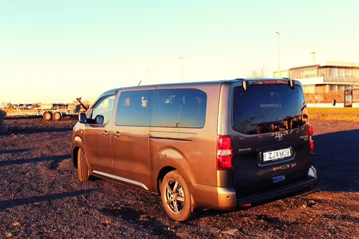 Gray Toyota Hiace van parked at Keflavik airport area during golden hour, rear view