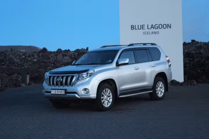 Silver Toyota Land Cruiser SUV parked at Blue Lagoon Iceland sign for private airport transfer