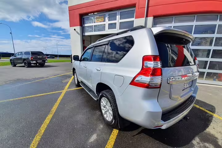 Silver Toyota Land Cruiser SUV parked outside building in Iceland for airport transfer service
