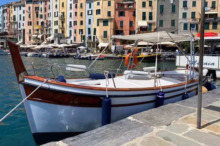 Traditional boat docked in front of colorful buildings in La Spezia, perfect for a Golfo Dei Poeti sunset tour.
